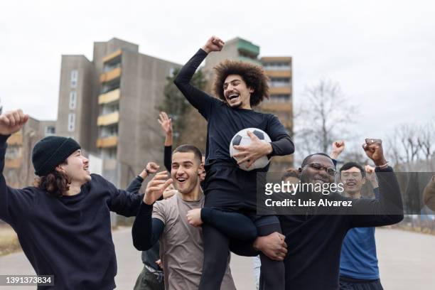 winning football team cheering on playing field - football player stock-fotos und bilder