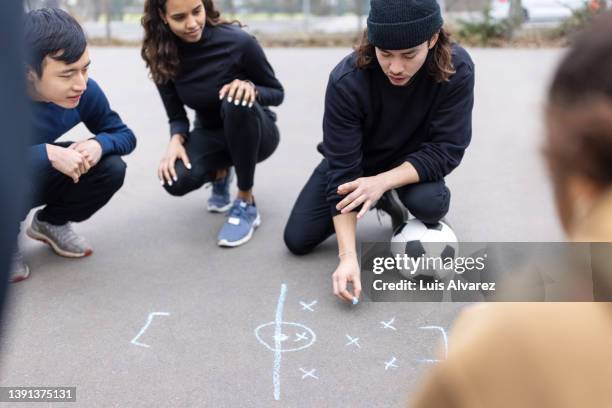 soccer team discussing a game strategy on ground - football game plan stock pictures, royalty-free photos & images