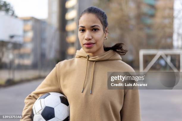 portrait of young woman holding soccer ball on sports court in the city - urban football pitch stock pictures, royalty-free photos & images