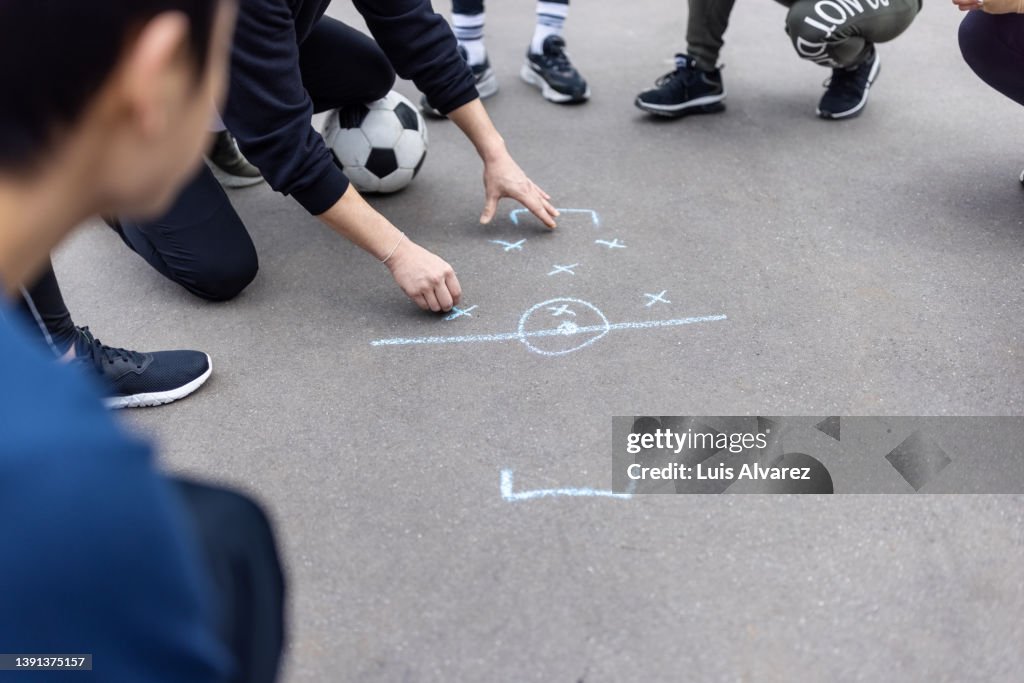 Soccer team planning the game strategy using drawing it on the ground