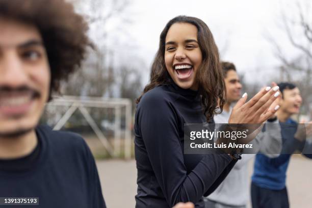 woman clapping hands with friends standing in circle at playing ground - german football association stockfoto's en -beelden