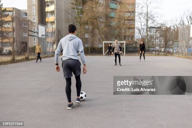 young people playing football in urban soccer court - essayer de marquer photos et images de collection