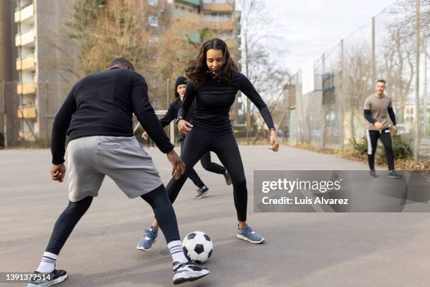 group of men and women playing soccer outdoors in the city - man tackling stock pictures, royalty-free photos & images
