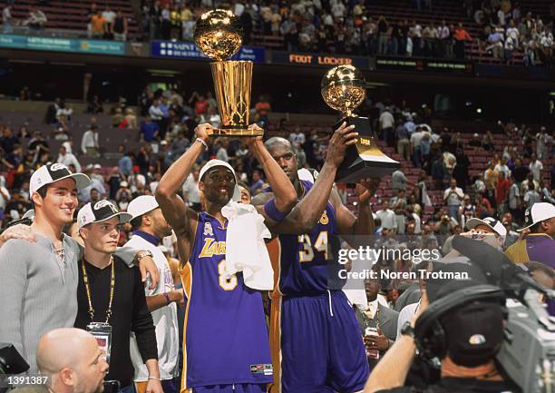 Guard Kobe Bryant of the Los Angeles Lakers holds up the championship trophy as center Shaquille O'Neal holds up his Finals Series MVP trophy after...