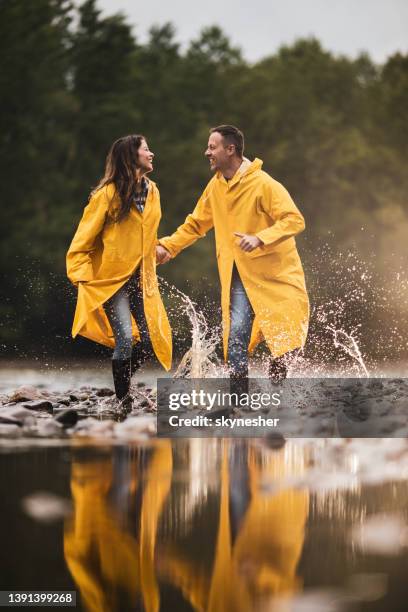 young carefree couple having fun by the river. - regnkläder bildbanksfoton och bilder
