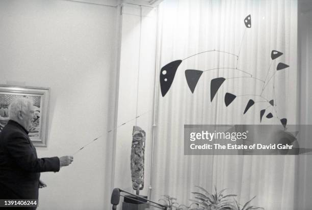 American sculptor and artist Alexander Calder poses for with one of his mobiles at Perls Gallery on East 78th Street in November 1964 in New York...