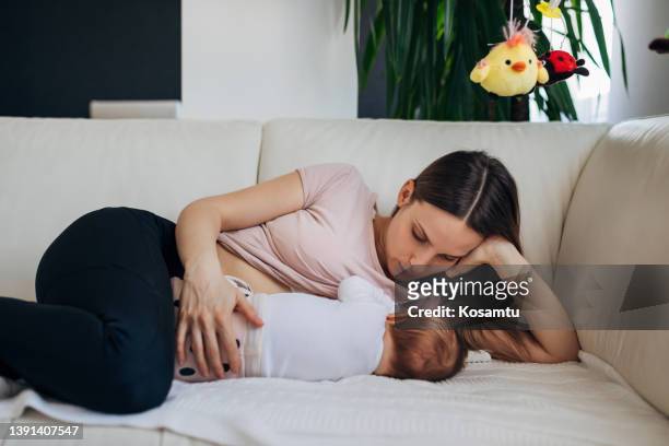 baby's first days of life in family at home. the caring mother lies next to the baby and breastfeeding her daughter - flat chested woman 個照片及圖片檔