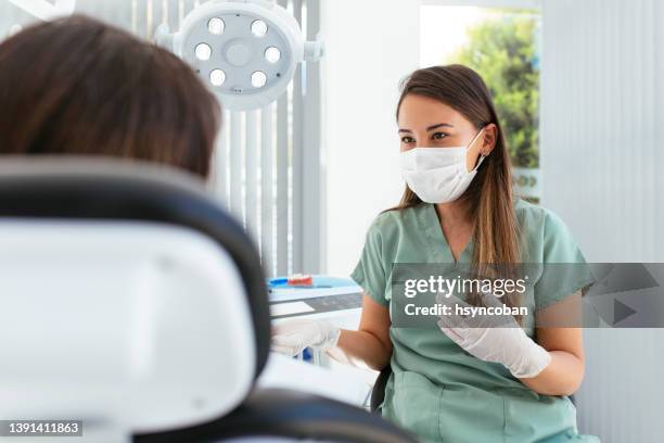 female dentist talking to her patient at dentist's office - periodontal disease stock pictures, royalty-free photos & images