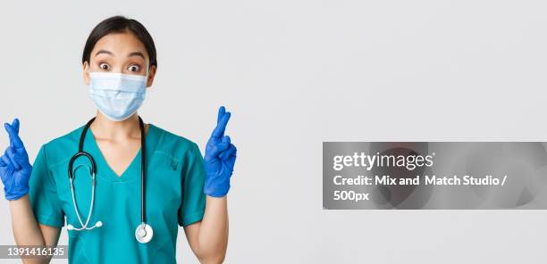 portrait of young asian female medical worker wearing medical gear on white background - nurse praying stock pictures, royalty-free photos & images