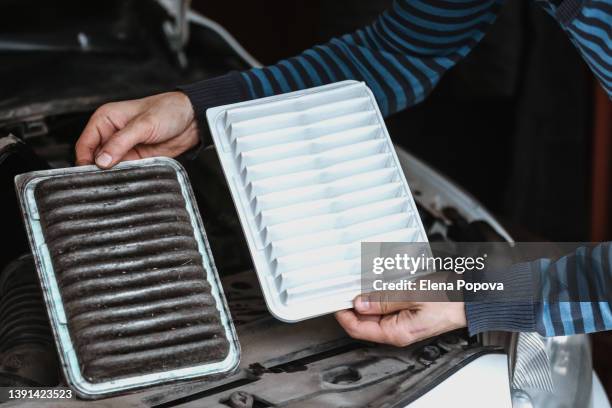 auto mechanic repairing car and changing air purifier. holding used car filter and new one - air purifier stock pictures, royalty-free photos & images