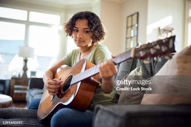 teenage girl plays guitar on the sofa. - songwriter stock pictures, royalty-free photos & images