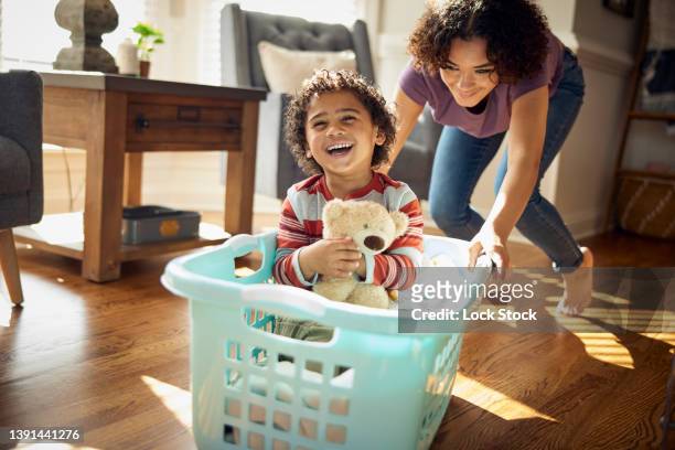 Older sister gives younger brother a ride in the laundry basket.