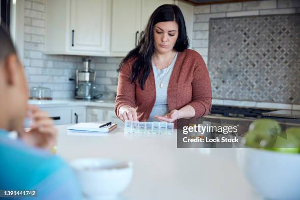 woman putting medications in a daily pill organizer - pill container stock pictures, royalty-free photos & images