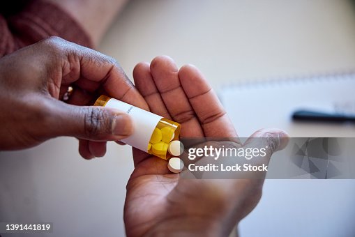 African American man pouring medications out of a bottle into his hand. African American man pouring medications out of a bottle into his hand.
