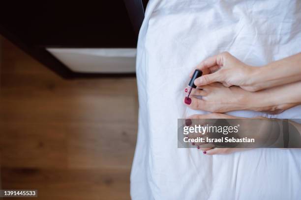 woman painting her toenails on the bed. - toenail stock-fotos und bilder