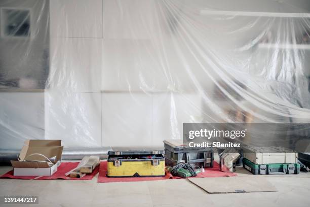 tarps covering living room surfaces undergoing renovation - tarpaulin stock pictures, royalty-free photos & images