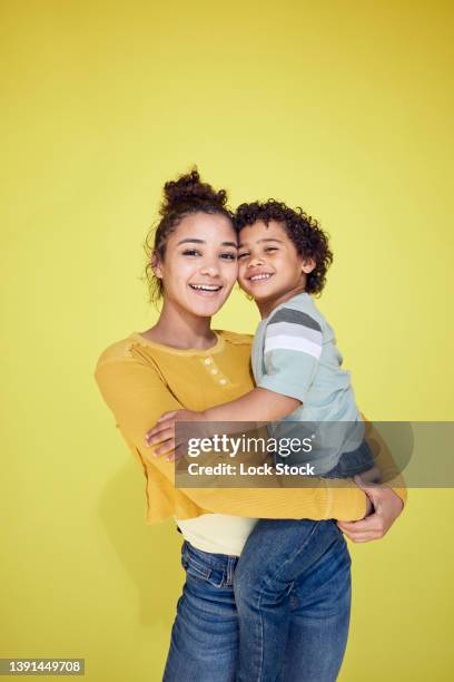 sister and younger brother on yellow background. - family on coloured background stock pictures, royalty-free photos & images