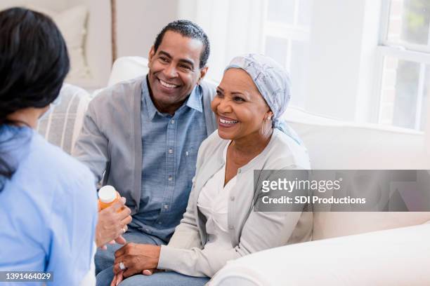 älteres ehepaar lächelt, während es der krankenschwester zuhört - doctor smile stock-fotos und bilder