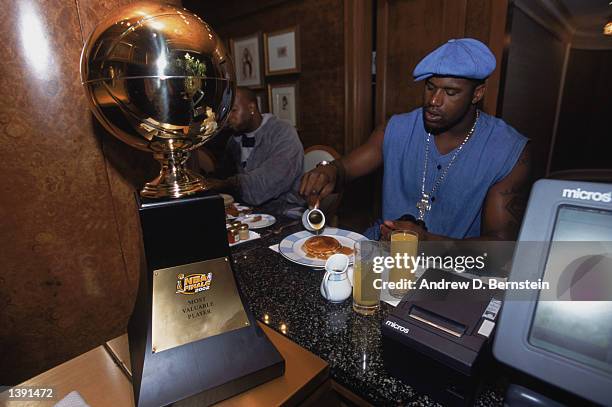 Center Shaquille O'Neal of the Los Angeles Lakers eats his breakfast with his Series MVP trophy at hand the day after winning Game Four of the 2002...