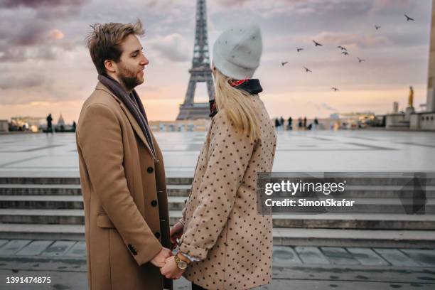 homme souriant à sa petite amie, debout l’un près de l’autre devant le parvis des droits de l’homme, paris - paris hiver photos et images de collection