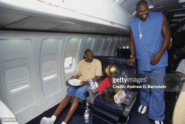 Center Shaquille O'Neal of the Los Angeles Lakers stands in the aisle of the team charter plane as guard Kobe Bryant eats his breakfast with the...
