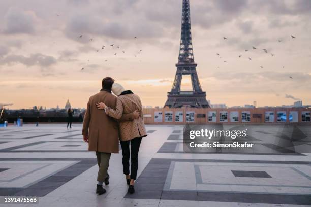 couple walking on parvis des droits de l'homme hugging and leaning at each other in the evening - couple paris stock pictures, royalty-free photos & images