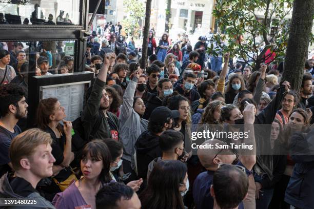 Protesters raise fists toward fellow students on the rooftop of the Sorbonne University, which has been occupied by a group of students as they...