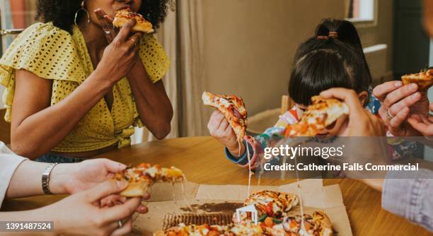 a group of people tuck in to hot pizza that has just been delivered - black knob stock pictures, royalty-free photos & images