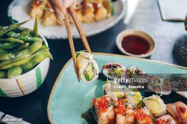 frau isst sushi-brötchen - serving dish stock-fotos und bilder
