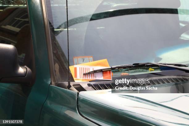 violation ticket for illegal parking on a vehicles windshield - ruitenwisser auto stockfoto's en -beelden