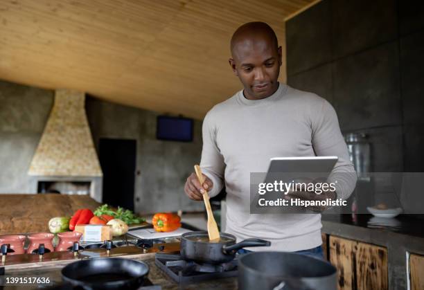 happy man cooking at home following an online recipe - dinner program stock pictures, royalty-free photos & images