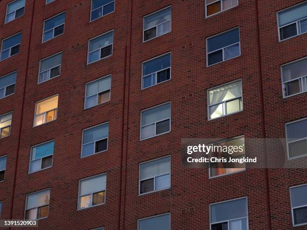 windows - some with lights on some without - on a tall brick building. - toronto night stock pictures, royalty-free photos & images