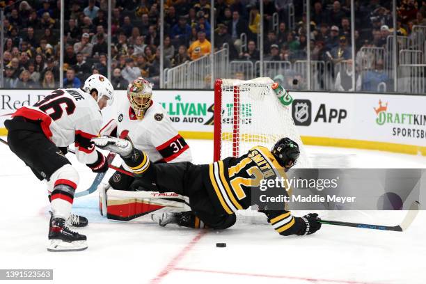 Craig Smith of the Boston Bruins slides in front of Colin White and Anton Forsberg of the Ottawa Senators during the third period at TD Garden on...