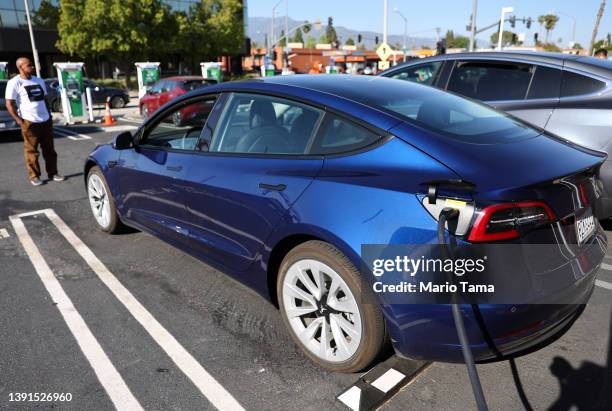 Jeffrey Hall waits as his Tesla car recharges at a Tesla Supercharger station on April 14, 2022 in Pasadena, California. California has unveiled a...