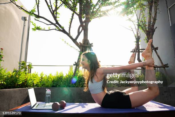 beautiful woman learning yoga class from internet laptop on holiday. - international day of yoga in bangkok stock pictures, royalty-free photos & images