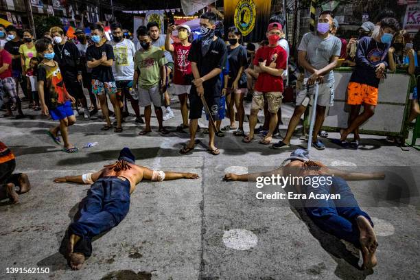 Flagellants with bloodied backs lie on the ground as they perform Good Friday Lenten Rites on April 15, 2022 in Navotas, Metro Manila, Philippines....