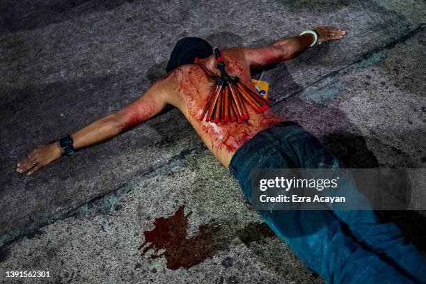 Flagellant with a bloodied back lies on the ground as he performs Good Friday Lenten Rites on April 15, 2022 in Navotas, Metro Manila, Philippines....