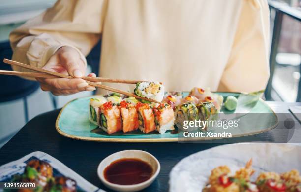 frau isst sushi-brötchen - woman sushi stock-fotos und bilder