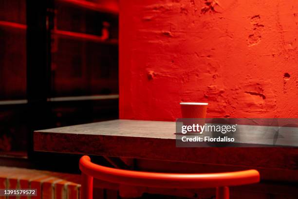 a red corrugated disposable paper coffee cup lying on a gray concrete table against a painted wall. takeaway, coffee to go. the concept of environmental pollution, recycling, recycling - ahead of the pack photos et images de collection