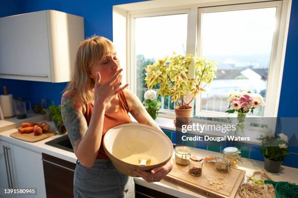 woman tasting cake mixture whilst baking in her kitchen. - woman baking stock-fotos und bilder