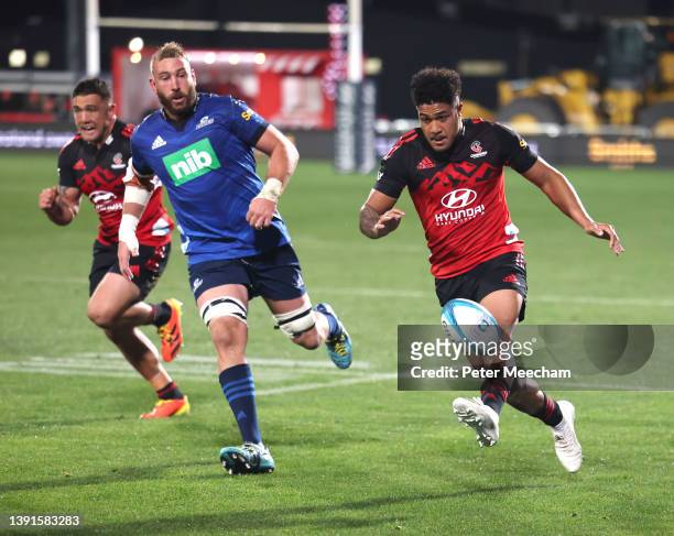 Leicester Fainga'anuku from The Crusaders kicks as team mate Codie Taylor and Luke Romano from the Blues give chase during the round four Super Rugby...