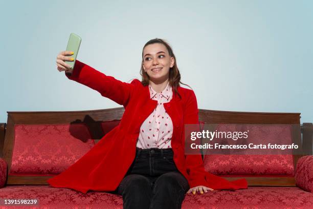 woman taking selfies while relaxing on her couch - fashion oddities stock pictures, royalty-free photos & images