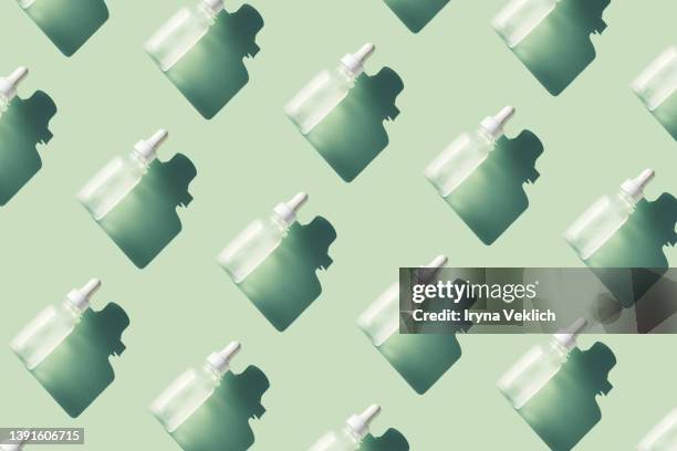 skin care pattern made with bottles with beauty product facial serum or essential oil on pastel mint green turquoise color background. - mint green stock pictures, royalty-free photos & images