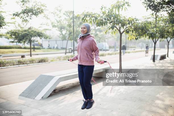 young asian hijab woman jumping rope, skipping, public park - sautiller photos et images de collection