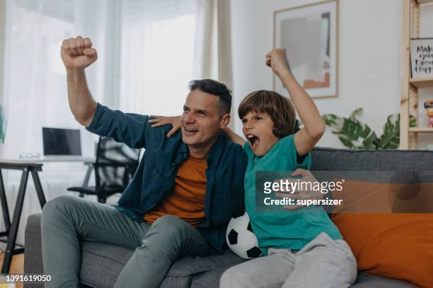 dos generaciones de aficionados al fútbol - familia viendo la television fotografías e imágenes de stock