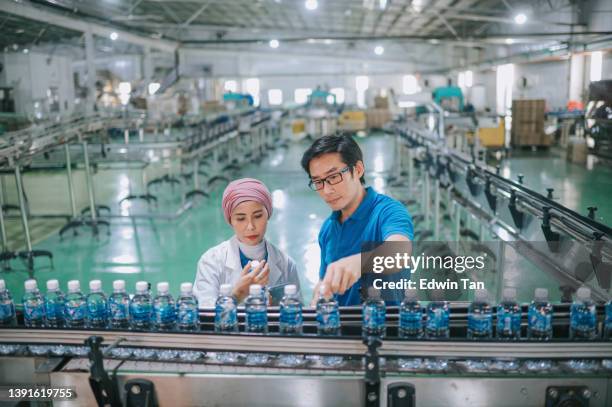 asian malay inspector examining quality of mineral water in mineral water factory production line - bottling plant stock pictures, royalty-free photos & images