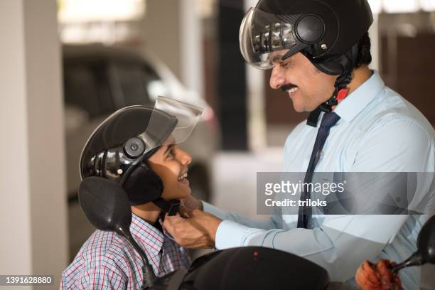 father adjusting helmet of son before leaving for school and office - sports helmet stock pictures, royalty-free photos & images