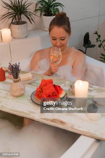 woman takes a bath with foam and drink wine - badewanne mit obst stock-fotos und bilder