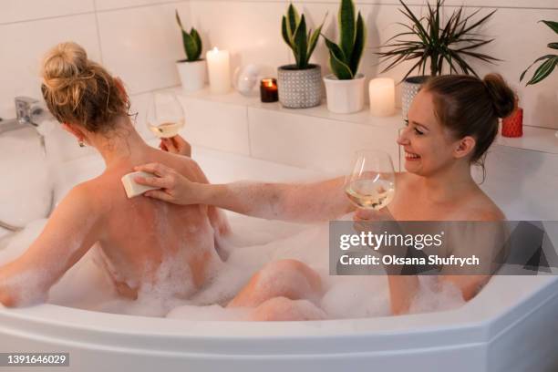 two woman take a bath with foam - champagne salon stock-fotos und bilder