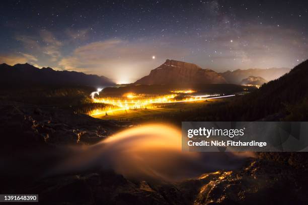 cascade falls lit up by highway lights in banff national park - weltraum und astronomie stock-fotos und bilder